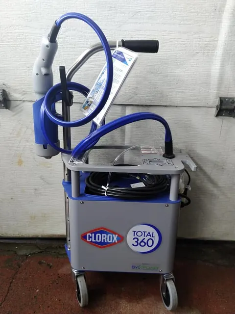 Clorox Total 360 electrostatic sprayer on a wheeled cart with blue hoses and a handheld wand